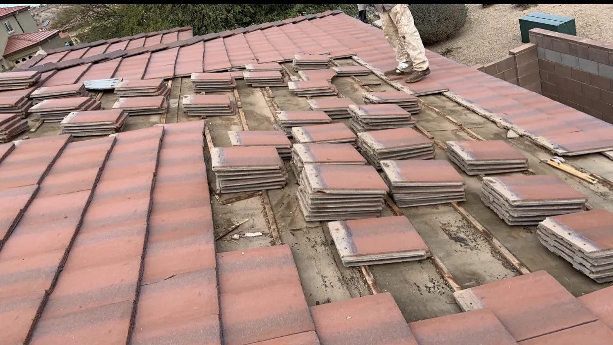 Tiles lifted to reveal the underlayment membrane beneath a tile roof during a DC Roofing inspection