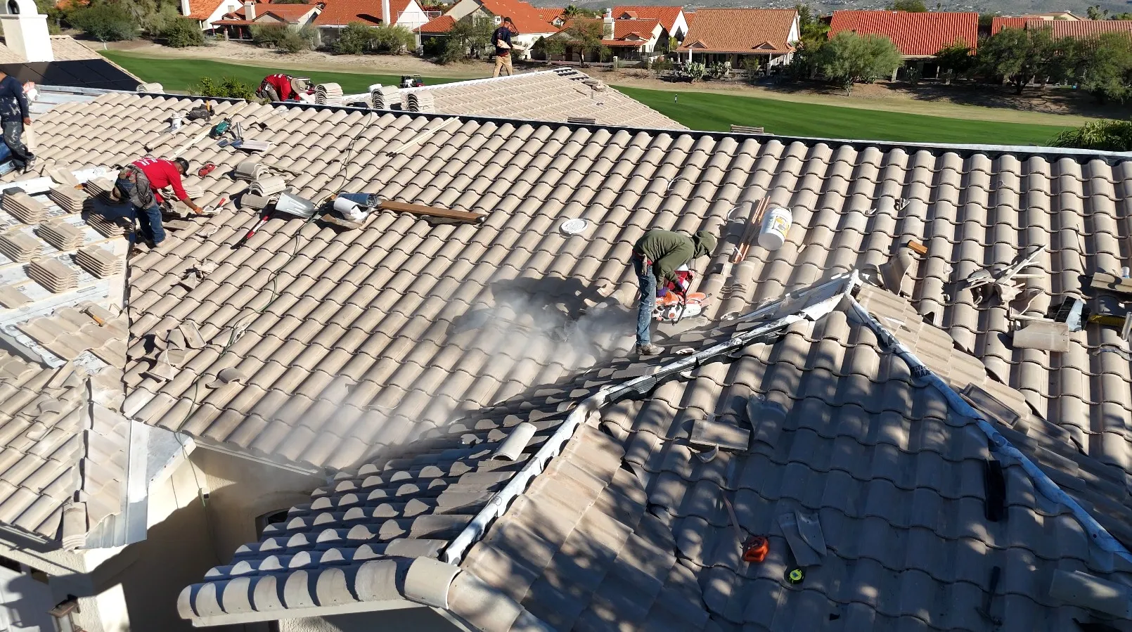 DC Roofing crew restoring a tile roof on an Oro Valley home with green fairway in background