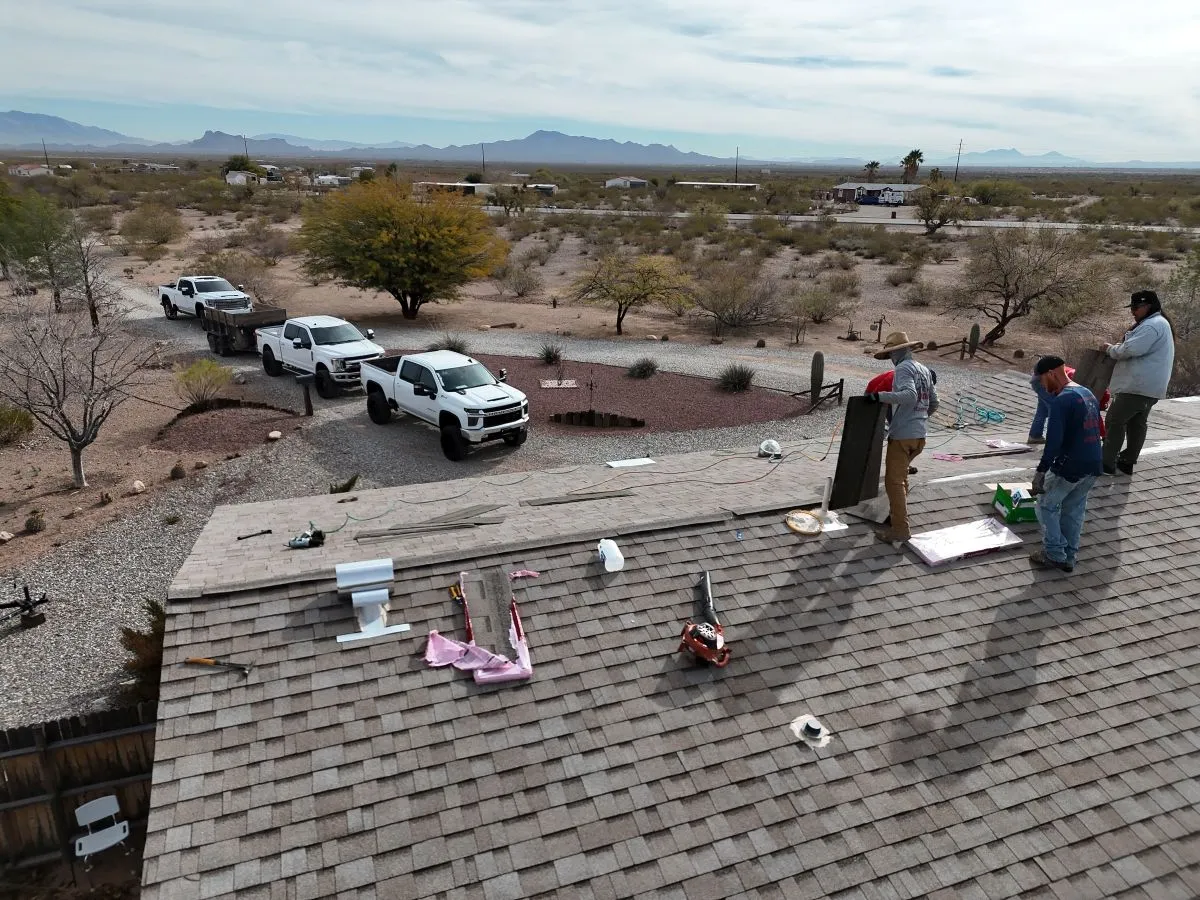 DC Roofing crew working on a shingle roof in Vail, Arizona with open desert landscape in background
